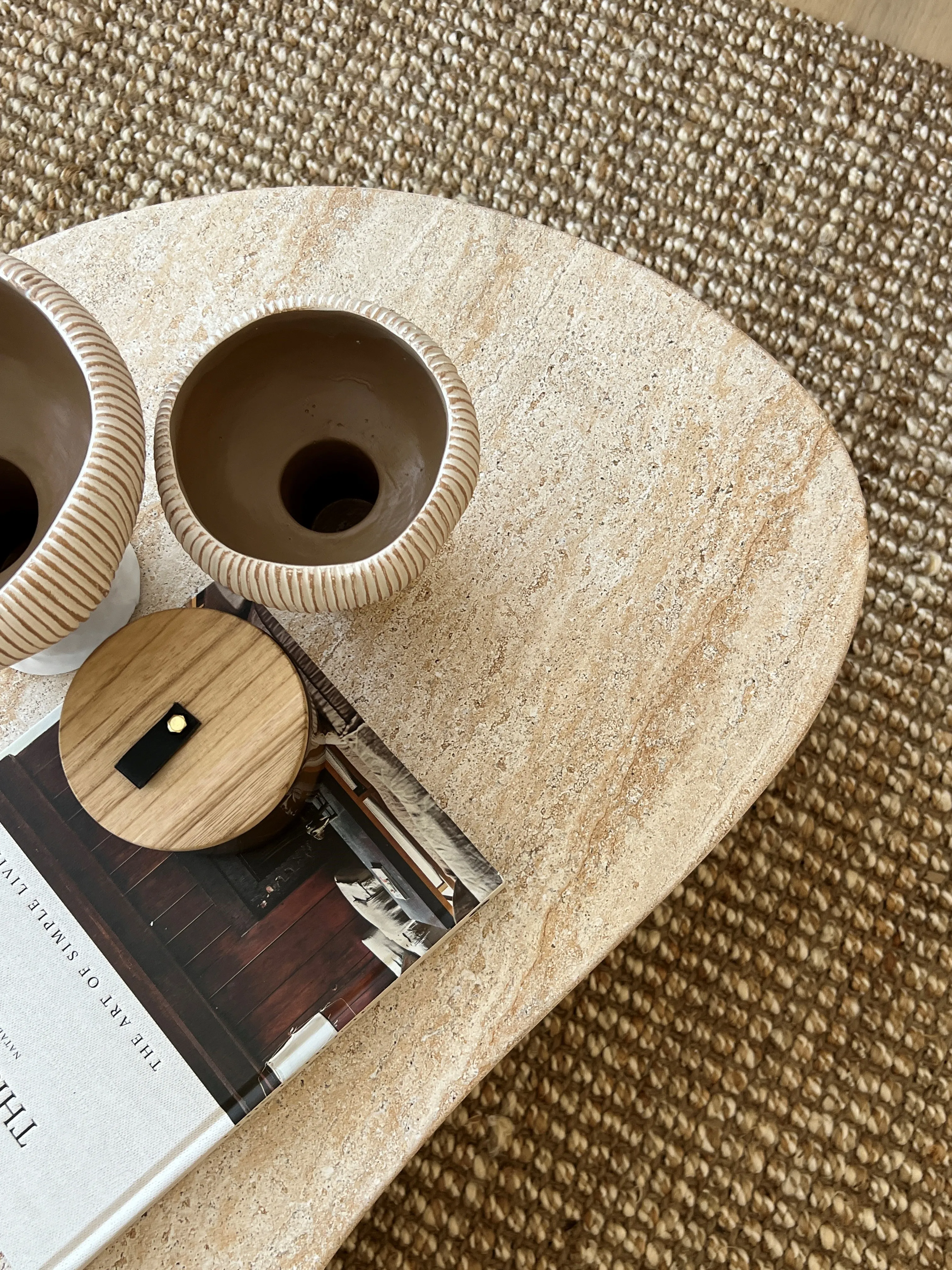 Travertine coffee table detail with ceramic vessels and design book